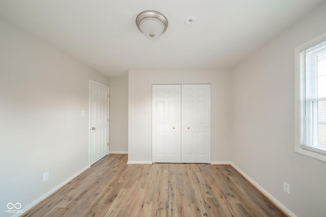 unfurnished bedroom with light wood-style floors, a closet, and baseboards