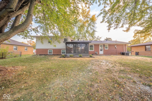 rear view of house with a sunroom, brick siding, and a yard