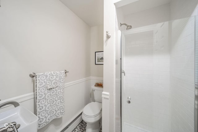 bathroom featuring toilet, a shower stall, and wainscoting