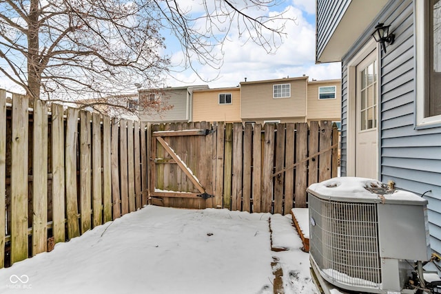 yard layered in snow featuring a gate, fence, and cooling unit