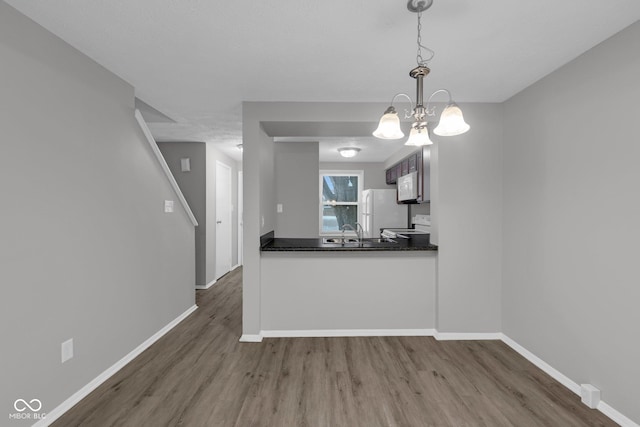 kitchen with dark wood-style floors, dark countertops, decorative light fixtures, and baseboards