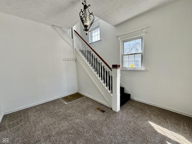 staircase featuring carpet and a textured ceiling