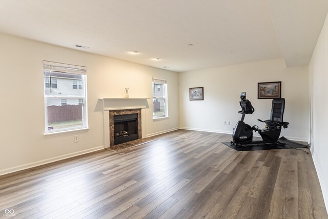 workout room with visible vents, a fireplace, baseboards, and wood finished floors