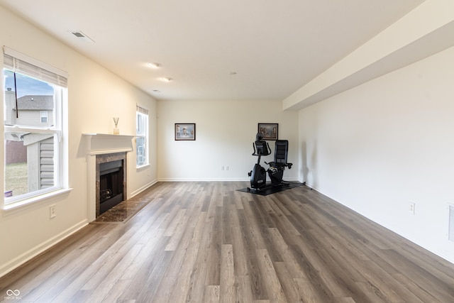 unfurnished living room with visible vents, baseboards, wood finished floors, and a high end fireplace