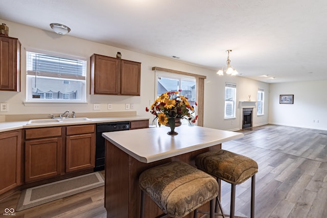 kitchen with wood finished floors, a fireplace, a sink, light countertops, and dishwasher