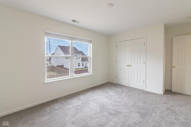 unfurnished bedroom with carpet, visible vents, a closet, and baseboards