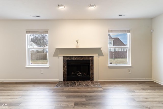 unfurnished living room with visible vents, baseboards, wood finished floors, and a fireplace