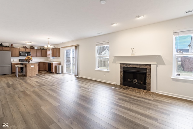 unfurnished living room with visible vents, a fireplace, baseboards, and wood finished floors