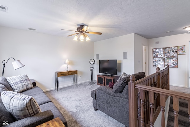 carpeted living room with a ceiling fan, baseboards, visible vents, and a textured ceiling