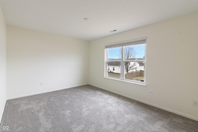 carpeted spare room featuring baseboards and visible vents