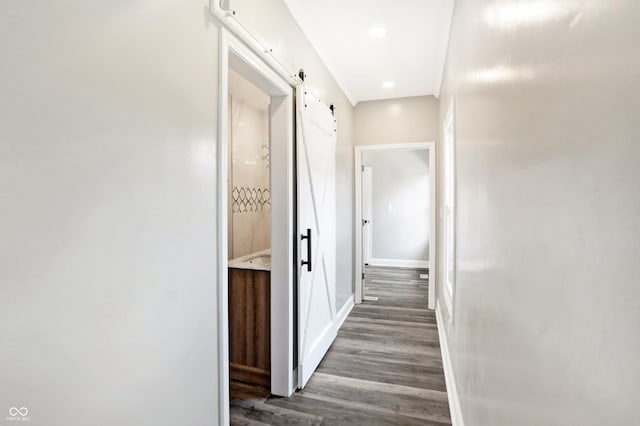 corridor featuring recessed lighting, baseboards, wood finished floors, and a barn door