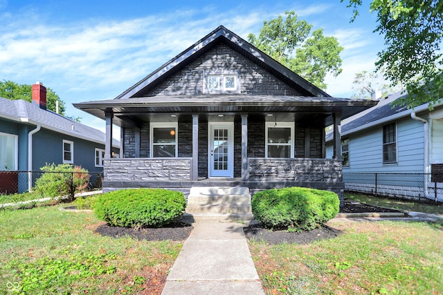 bungalow-style house featuring fence, a porch, and stone siding