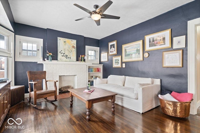 living room featuring radiator, dark hardwood / wood-style floors, ceiling fan, and a fireplace