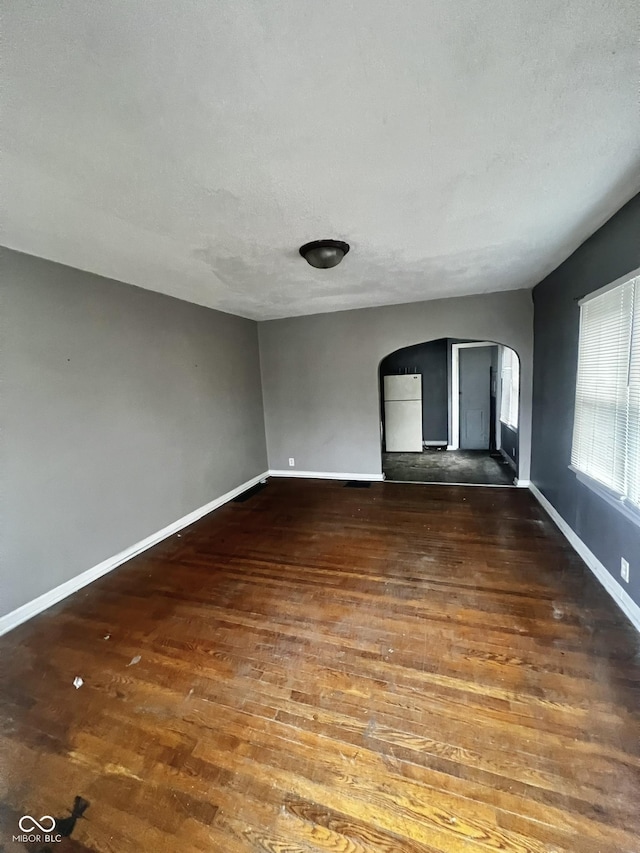 unfurnished room featuring a textured ceiling and dark hardwood / wood-style flooring