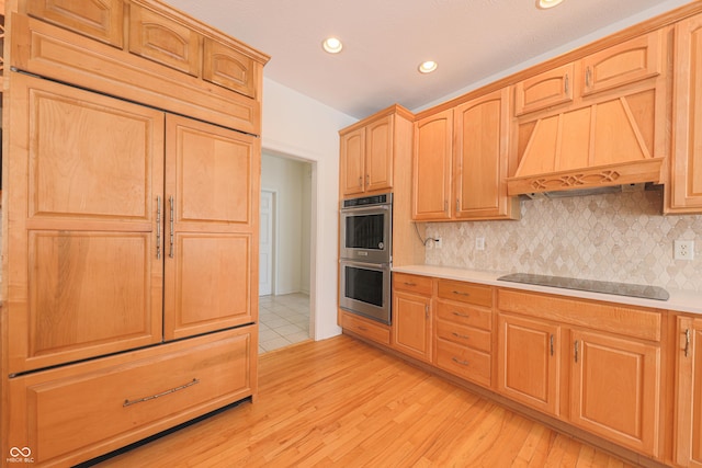 kitchen with light wood finished floors, light countertops, decorative backsplash, double oven, and black electric cooktop