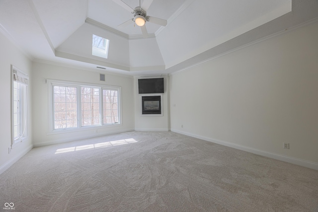 unfurnished living room featuring light carpet, ornamental molding, a glass covered fireplace, and baseboards