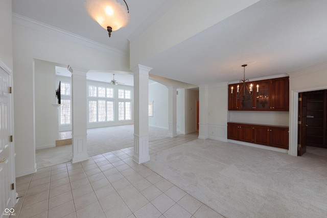 unfurnished living room featuring ornamental molding, light carpet, decorative columns, and ceiling fan with notable chandelier