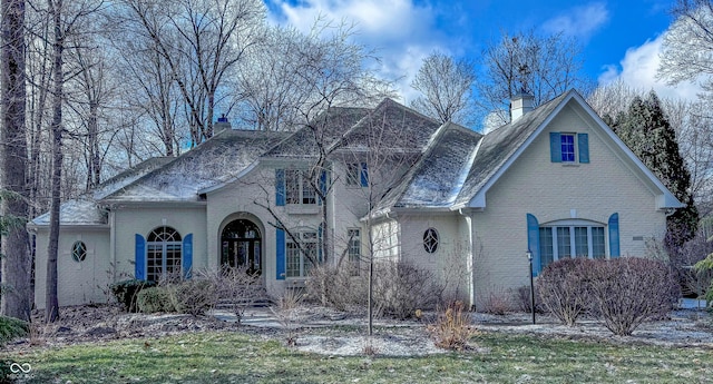 view of front of house with brick siding, a chimney, and a front lawn