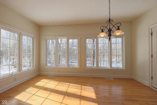 unfurnished dining area with a chandelier, light wood finished floors, visible vents, and baseboards