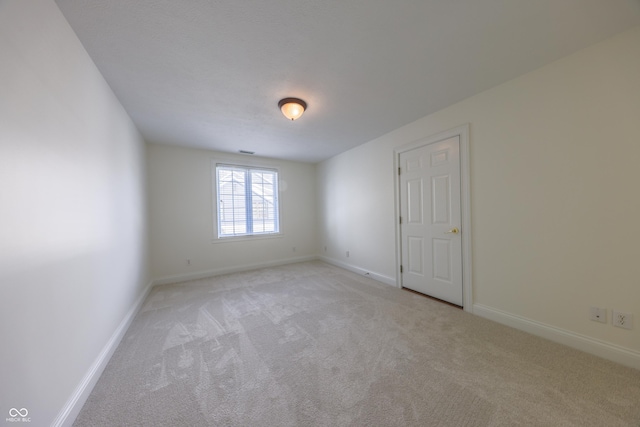 spare room featuring baseboards and light colored carpet