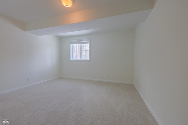 spare room featuring light colored carpet and baseboards