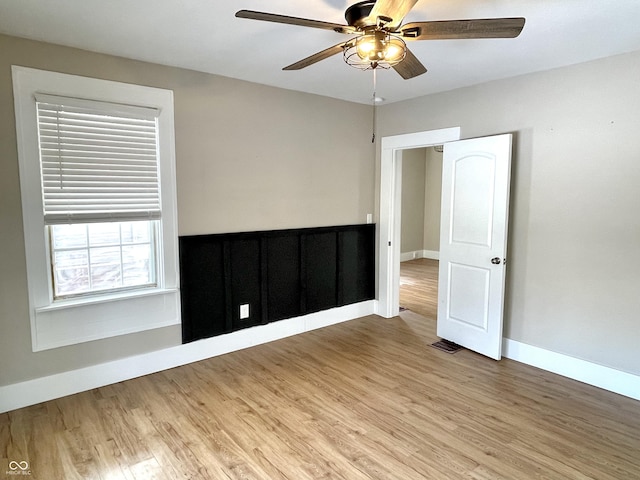 empty room with a ceiling fan, visible vents, baseboards, and wood finished floors