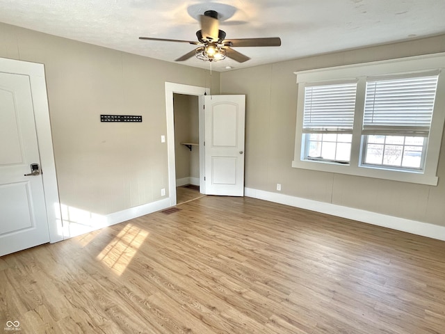 unfurnished bedroom featuring a ceiling fan, light wood-style flooring, baseboards, and a textured ceiling