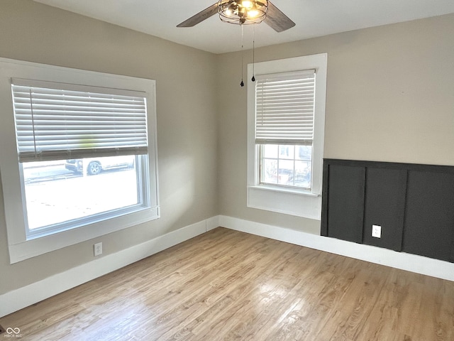 empty room featuring light wood-style floors, baseboards, and a ceiling fan