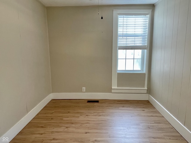 unfurnished room featuring light wood finished floors, visible vents, and baseboards