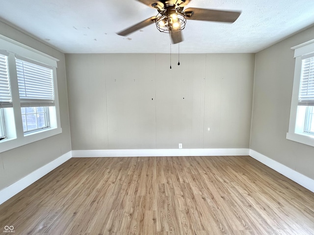 unfurnished room with light wood finished floors, baseboards, and a textured ceiling