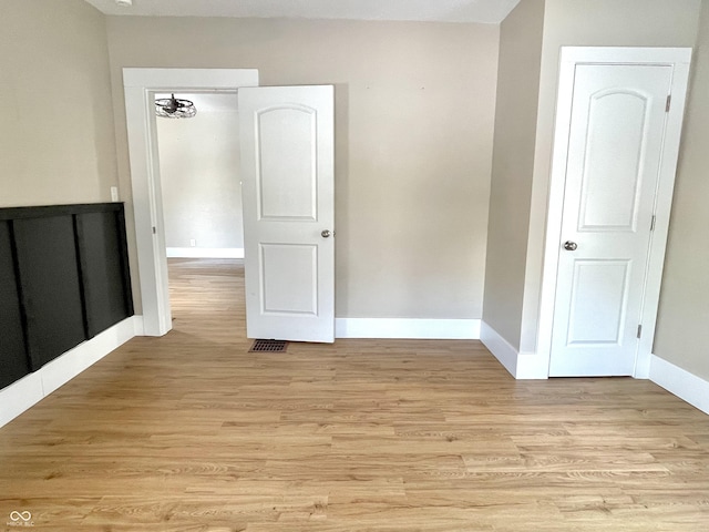 empty room with light wood-style flooring, visible vents, and baseboards