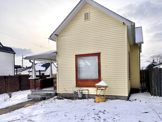 snow covered house featuring fence