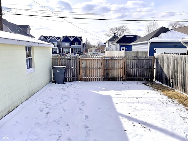 snowy yard featuring a residential view and fence