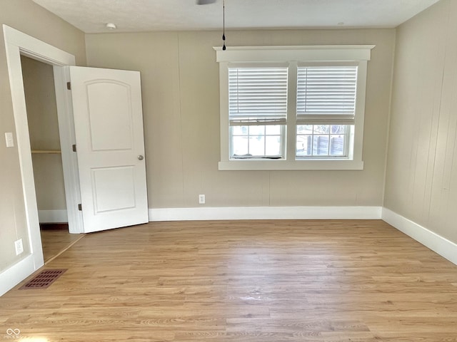 empty room featuring baseboards, visible vents, and light wood-style floors