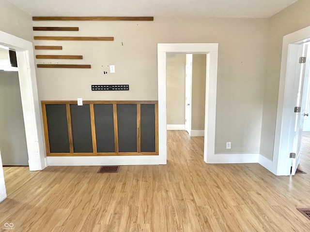 empty room featuring light wood finished floors, visible vents, and baseboards