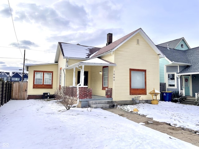 bungalow with a chimney, fence, and central AC