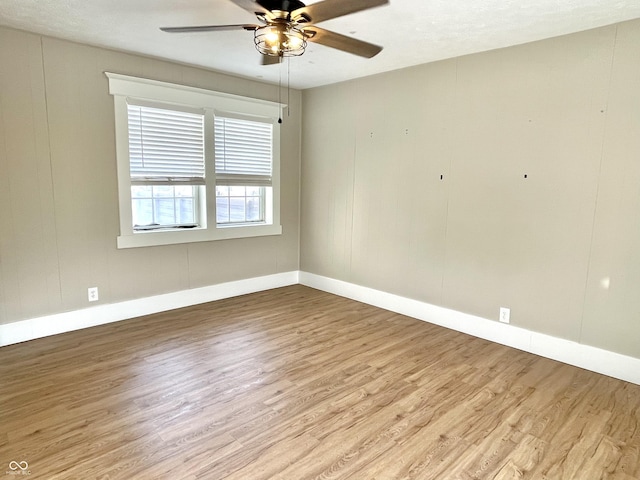 unfurnished room with ceiling fan, light wood finished floors, and baseboards