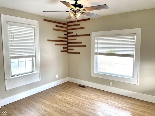 empty room featuring ceiling fan, light wood-type flooring, a wealth of natural light, and baseboards