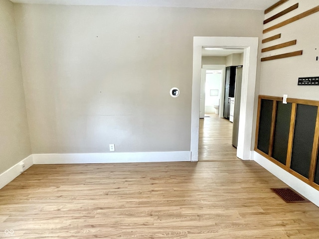 unfurnished room with light wood-type flooring, baseboards, and visible vents