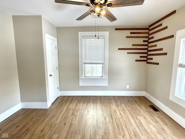 unfurnished room with light wood-style floors, baseboards, visible vents, and ceiling fan