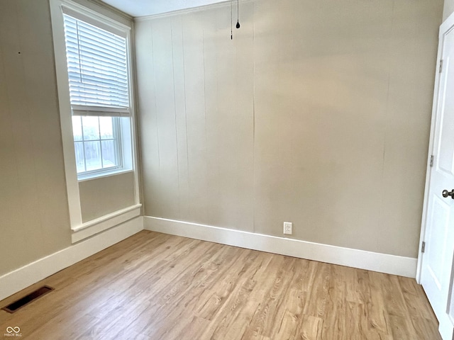 unfurnished room with light wood-type flooring, visible vents, and baseboards