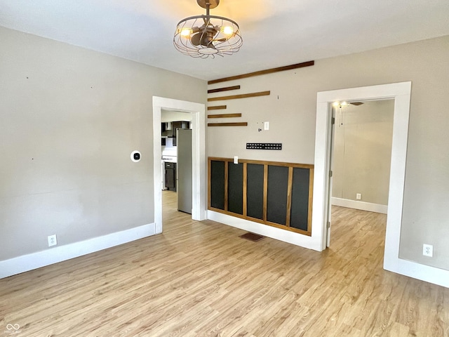 empty room with light wood-type flooring, visible vents, and baseboards