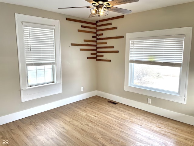 empty room featuring ceiling fan, light wood-type flooring, visible vents, and baseboards