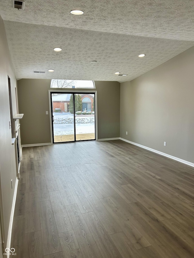 unfurnished room featuring a textured ceiling, baseboards, and dark wood-type flooring