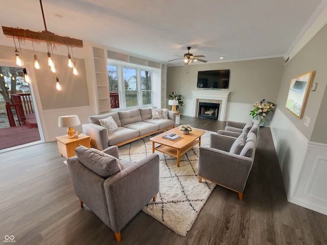 living room with a tile fireplace, crown molding, dark hardwood / wood-style flooring, ceiling fan, and built in features