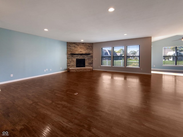 unfurnished living room featuring ceiling fan, a stone fireplace, and dark wood-type flooring