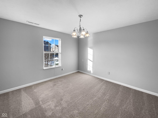 carpeted spare room featuring a notable chandelier