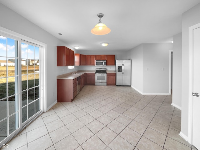 kitchen featuring sink, light tile patterned flooring, stainless steel appliances, and decorative light fixtures