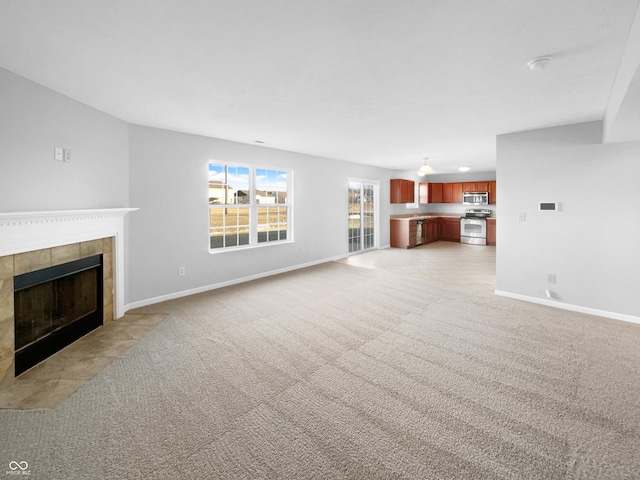 unfurnished living room featuring light carpet and a tiled fireplace