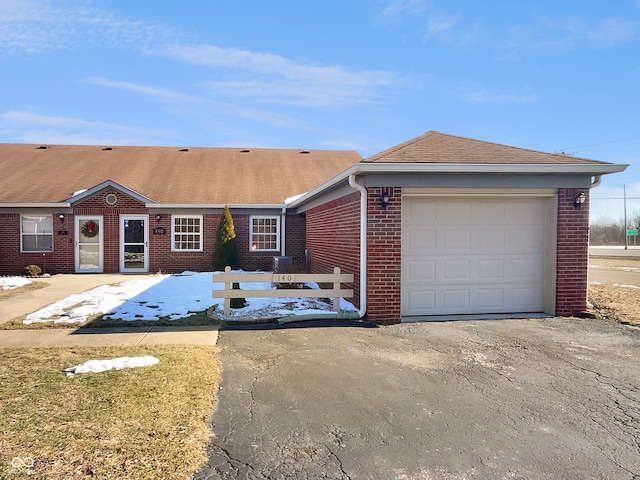 view of front of house with an attached garage, brick siding, fence, driveway, and roof with shingles